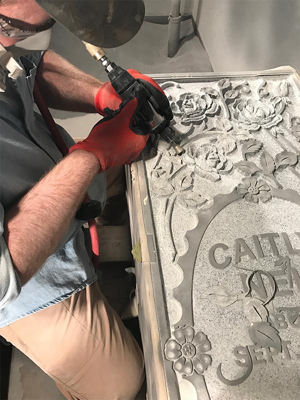 man engraving a custom designed headstone